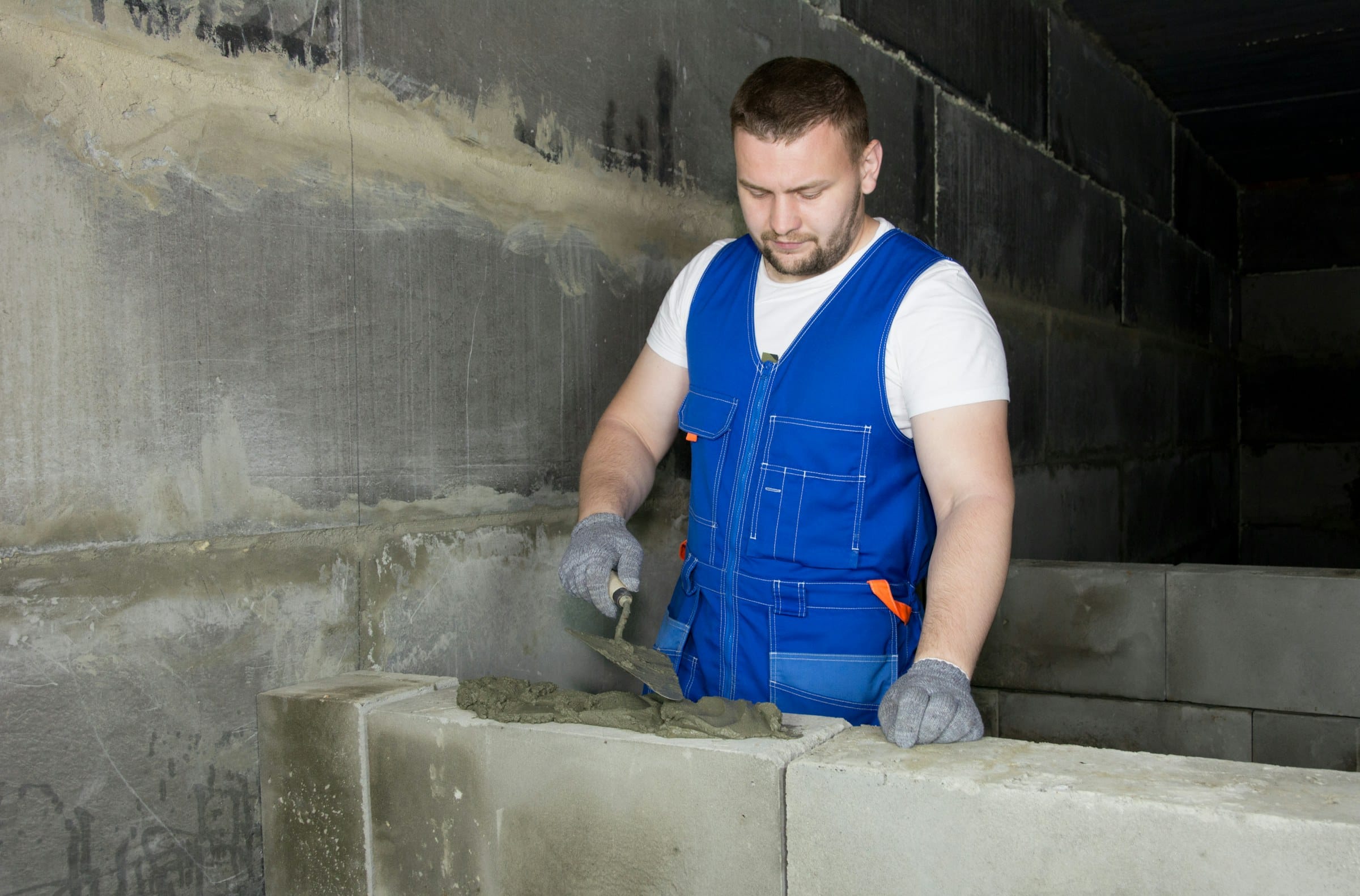 Bricklayer in overalls laying blockwork