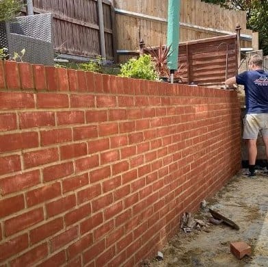 New red-brick garden wall, with the bricklayer still on site at the far end