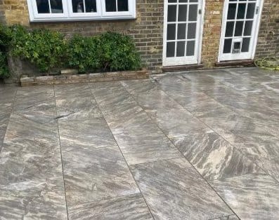 Large grey porcelain patio slabs laid outside French doors