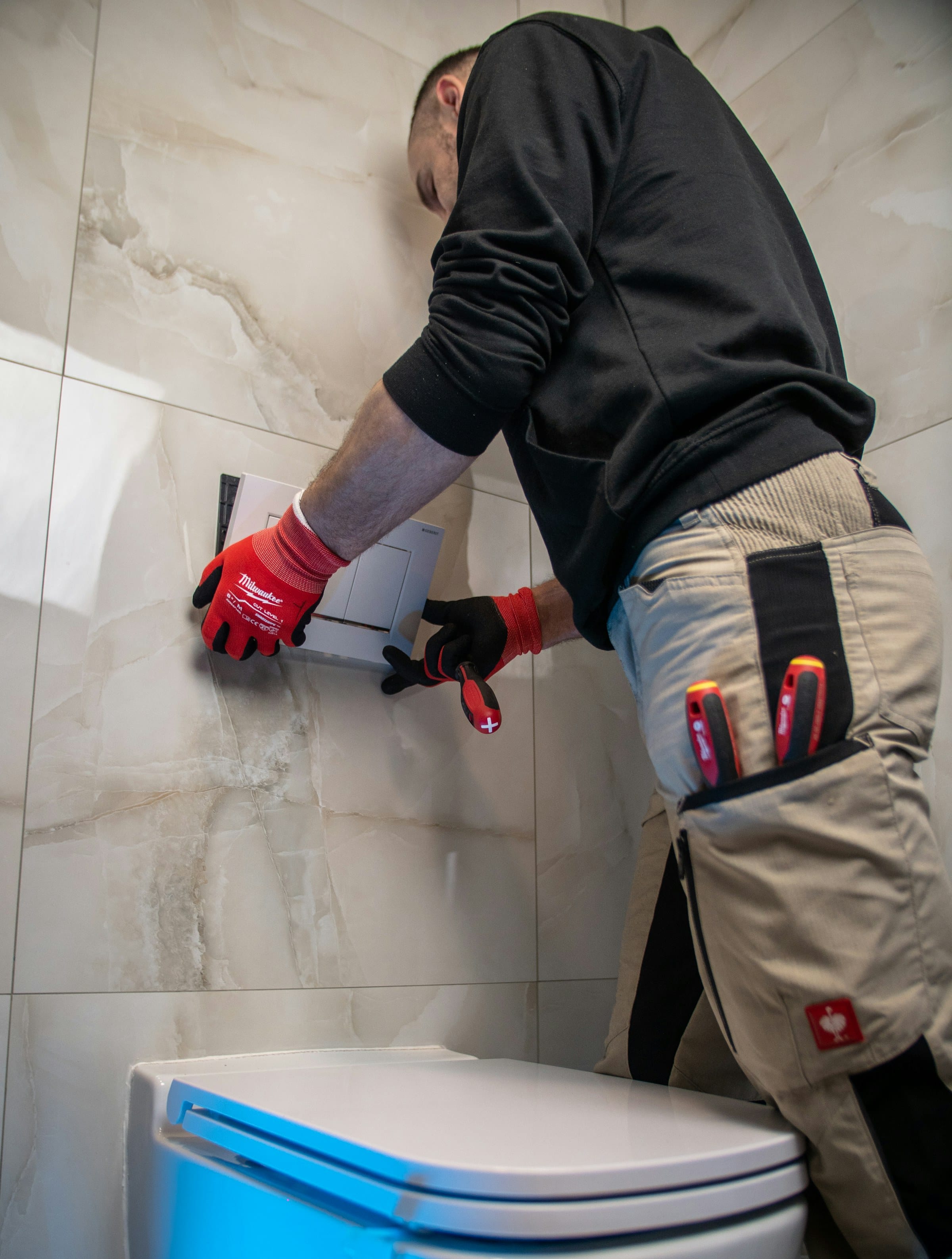 Tiler in work gloves setting a large-format wall tile