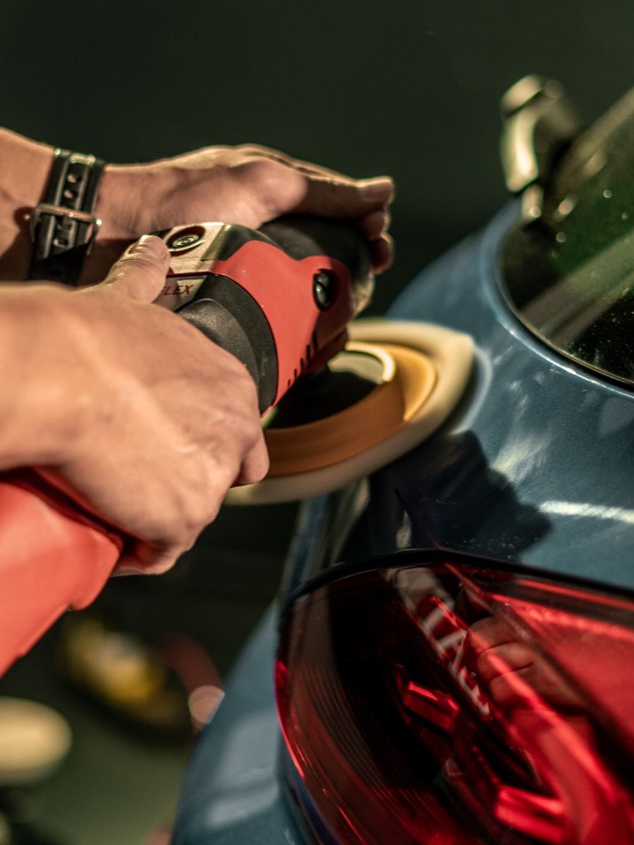 Car detailer polishing the paintwork of a car, photographed for a car detailing website
