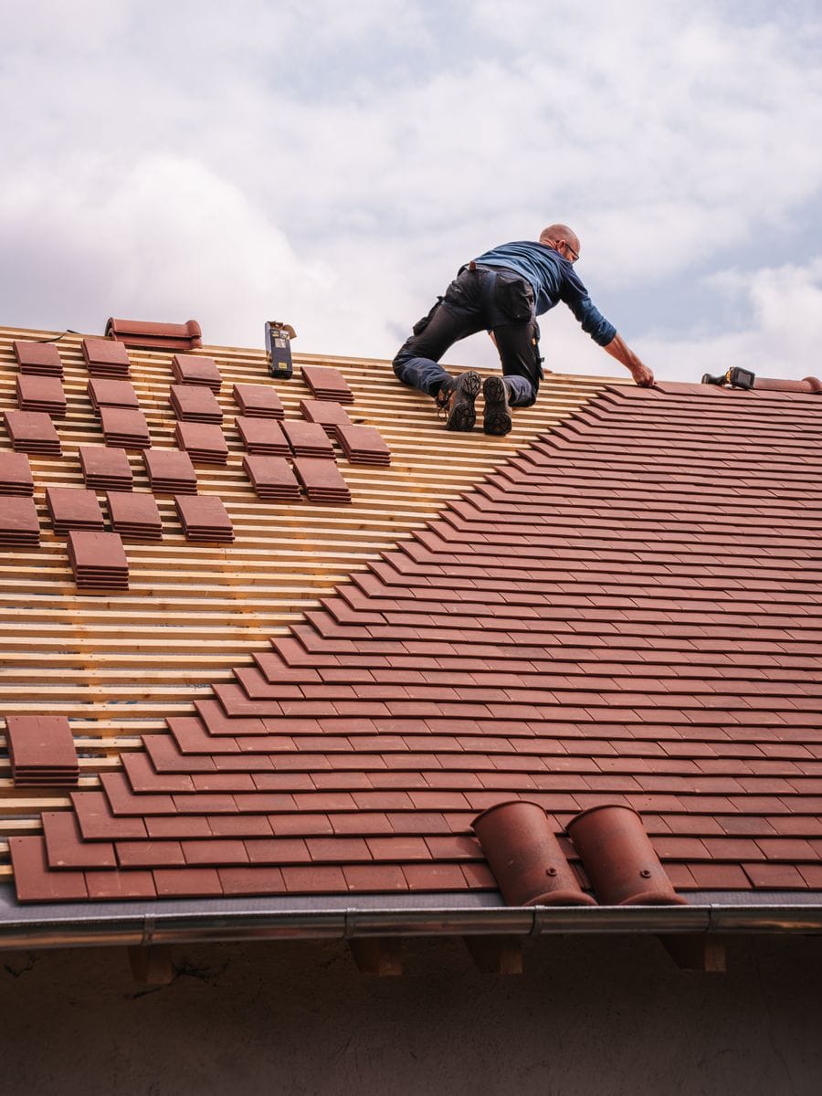 Roofer fixing new sheets on a pitched roof, photographed for a roofing website