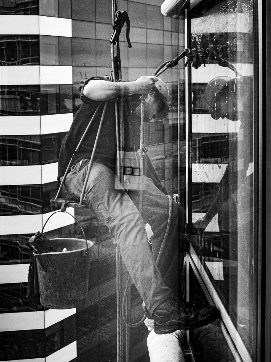 Window cleaner squeegeeing a large pane of glass, photographed for a window cleaning website