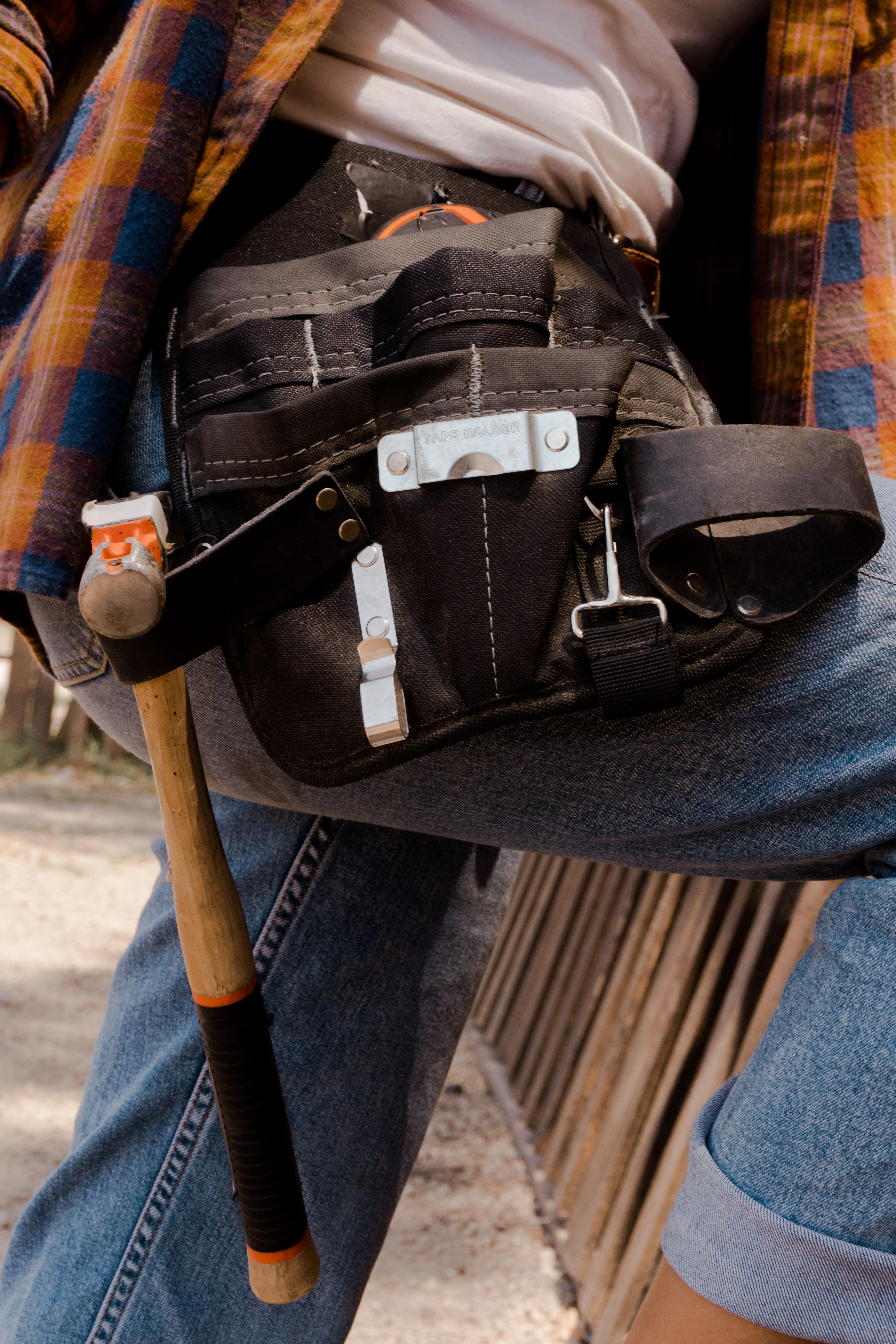 Professional UK handyman wearing a durable tool belt equipped with essential hand tools and measuring tape for residential home maintenance and repairs.