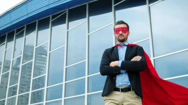 A man wearing a red cape in front of a building that's made from glass/